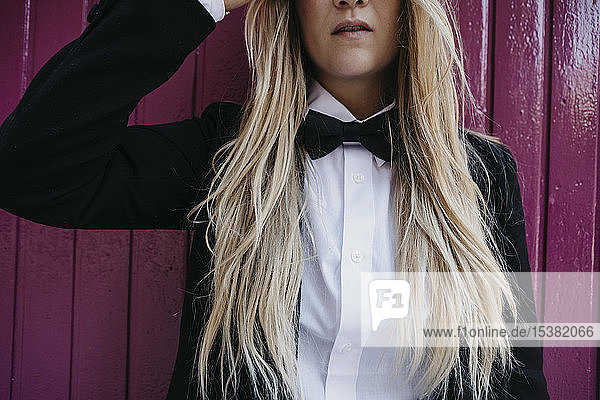 Blond young woman wearing black tie and blazer  partial view