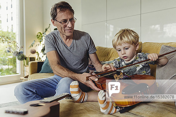 Porträt eines Kleinkindes beim Geigentest  während sein Vater zusieht