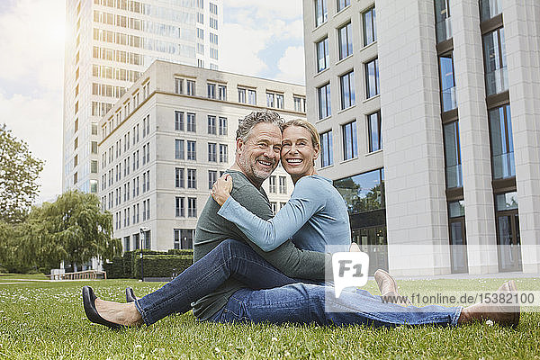 Glückliches reifes Paar sitzt auf dem Rasen in der Stadt