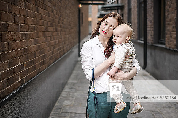 Mother holding her baby boy in an alley