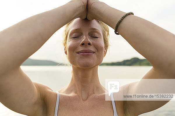 Porträt einer jungen Frau mit geschlossenen Augen an einem See