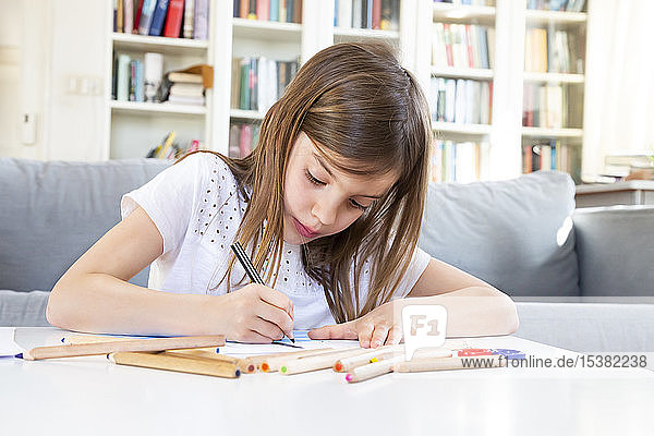 Portrait of girl drawing with coloured pencil at home