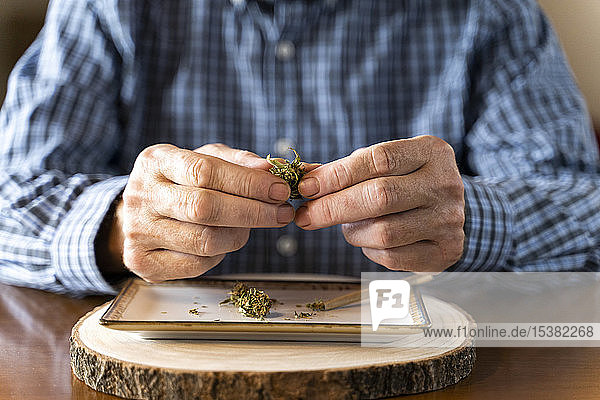 Älterer Mann zu Hause rollt Marihuana-Joint