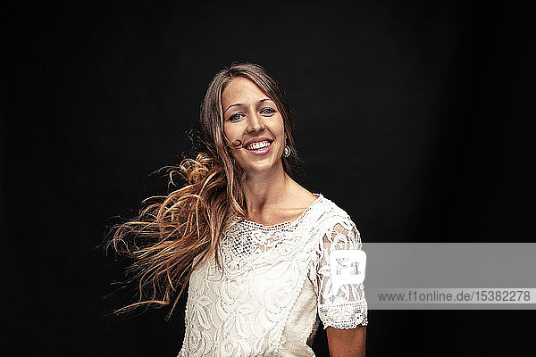 Portrait of happy young woman against black background