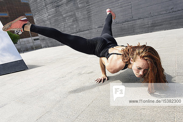 Sportliche junge Frau macht Akrobatik im Freien