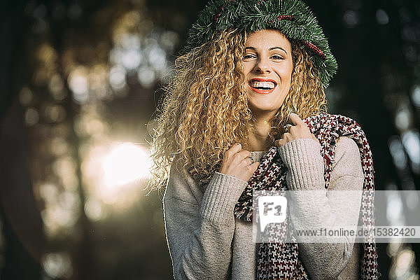 Porträt einer lachenden jungen Frau mit Weihnachtskranz auf dem Kopf