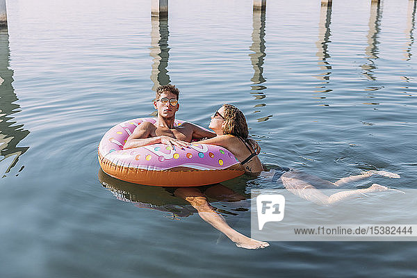 Junges Paar badet im Meer auf einem aufblasbaren Schwimmer in Donutform