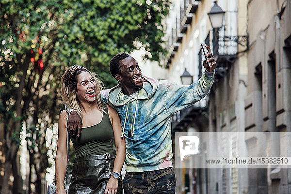 Porträt eines lachenden Paares  das sich mit einem Smartphone selbstständig macht  Madrid  Spanien