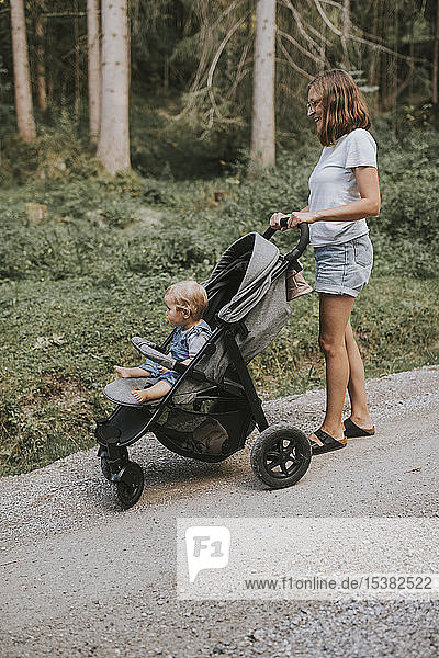 Mother with daughter in stroller on forest path