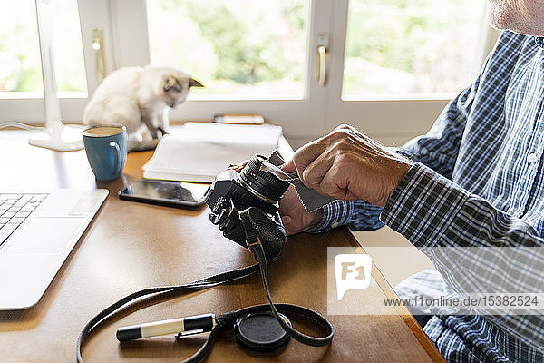 Älterer Mann reinigt Kamera zu Hause