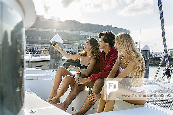 Drei junge Freunde  die einen Sommertag auf einem Segelboot genießen und ein Selfie