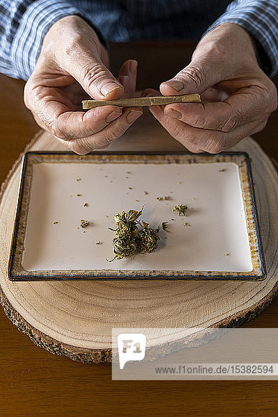 Älterer Mann zu Hause rollt Marihuana-Joint