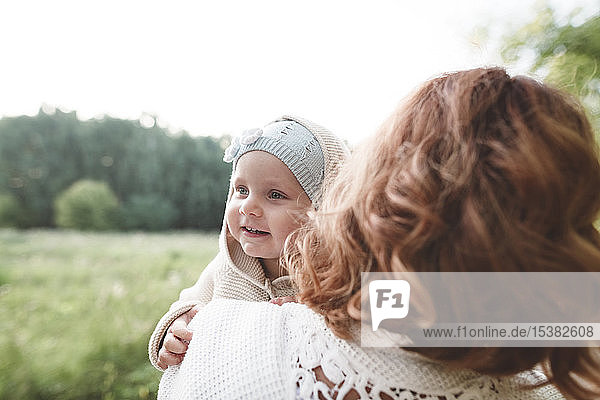 Happy little girl looking over mother's shoulder