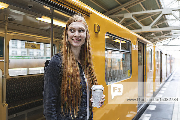 Porträt einer rothaarigen jungen Frau mit Kaffee zum Aussteigen aus dem Zug  Berlin  Deutschland