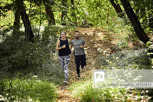 Sporty couple running on forest path