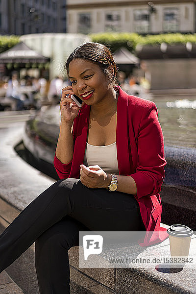 Porträt einer lächelnden Geschäftsfrau am Telefon  London  UK