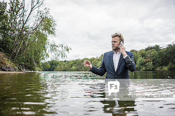 Businessman standing in a lake talking on the phone