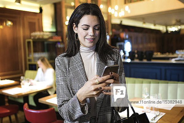 Geschäftsfrau benutzt Mobiltelefon in einem Restaurant