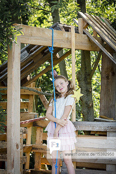 Girl dressed as a princess with crown and sceptre playing in a tree house