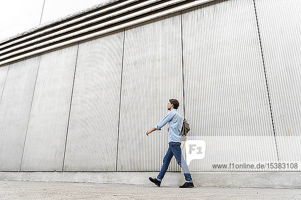 Casual businessman walking along a wall
