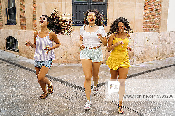 Drei glückliche Freundinnen laufen in der Stadt