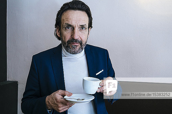 Porträt eines reifen Geschäftsmannes mit einer Tasse Kaffee in einem Cafe