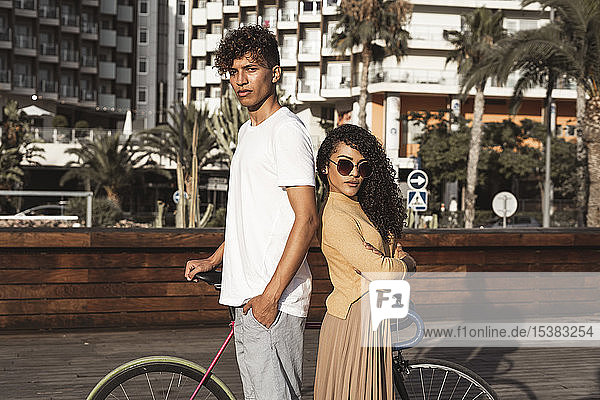 Cooles Paar mit Fahrrad in der Stadt  Rücken an Rücken stehend