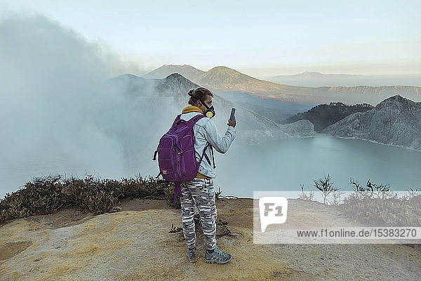 Man with respirator maskstanding at the edge of volcano Ijen  Java  Indonesia