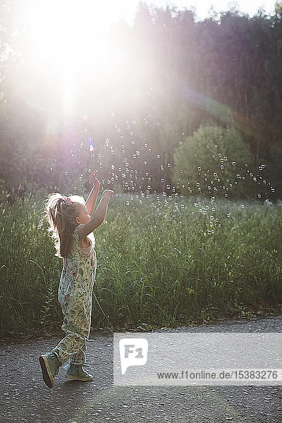Lttle girl catching soap bubbles in sunshine