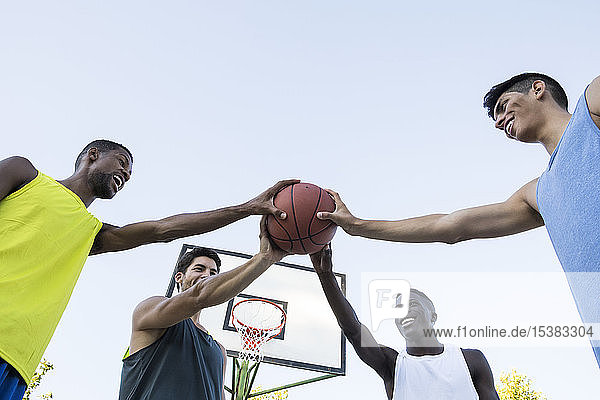 Gruppe gemischtrassiger Männer  die alle zusammen Basketball halten  niedriger Blickwinkel