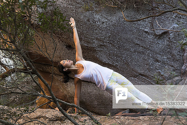 Junge Asiatin praktiziert Yoga auf einem Felsen  seitliche Plankenhaltung