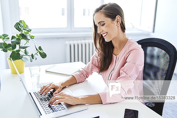 Fröhliche junge Geschäftsfrau arbeitet am Laptop im Home-Office
