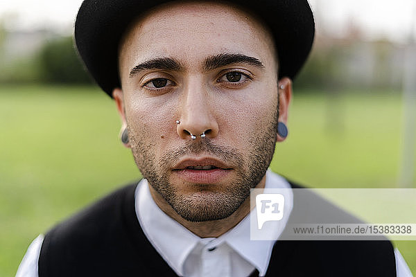 Portrait of young man with nose piercing and earrings