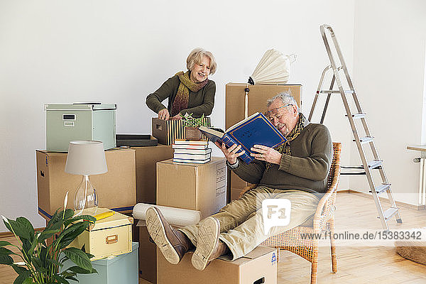 Älteres Ehepaar mit Fotoalbum umgeben von Pappkartons in einem leeren Raum