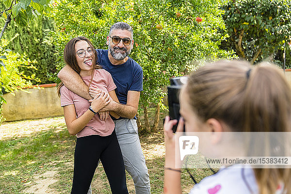 Mädchen macht ein Foto von glücklichem Vater mit Tochter im Garten