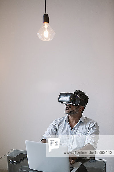 Geschäftsmann sitzt am Tisch und testet VR-Simulator