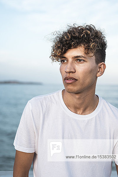 Porträt eines jungen Mannes mit lockigem Haar am Meer