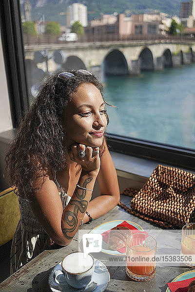 Porträt einer lächelnden jungen Frau  die am Frühstückstisch in einem Café sitzt  Lecco  Italien