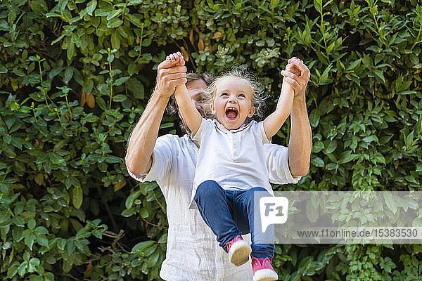 Happy father playing with little daughter in a park