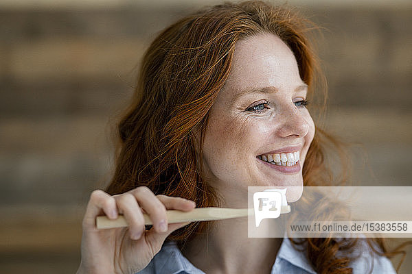 Porträt einer lachenden rothaarigen Frau mit Zahnbürste