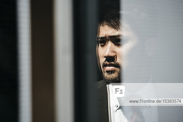 Porträt eines jungen Geschäftsmannes  der sich im Fenster spiegelt