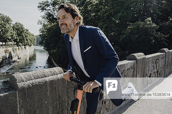 Businessman with e-scooter on a bridge