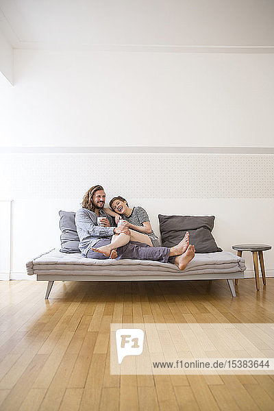 Glückliches junges Paar im Pyjama auf der Schlafcouch zu Hause