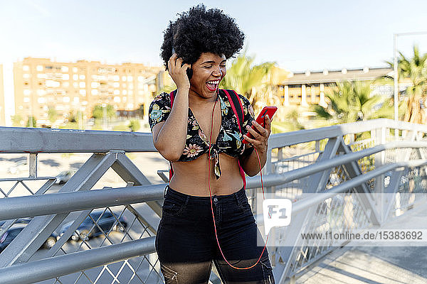Weibliche Afroamerikanerin mit Kopfhörern und Smartphone beim Musikhören