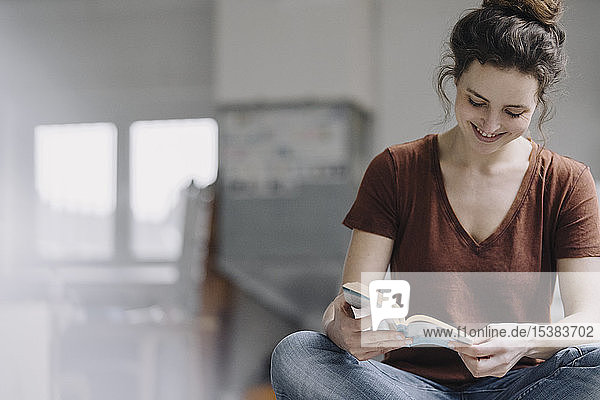 Lächelnde junge Frau liest ein Buch