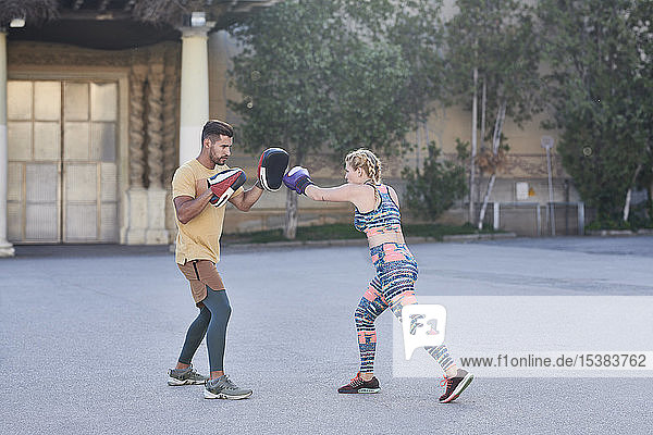 Fitnesstrainer übt Boxunterricht mit jungen Frauen im Freien in der Stadt