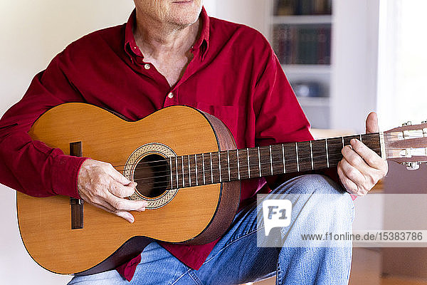 Älterer Mann spielt zu Hause Gitarre