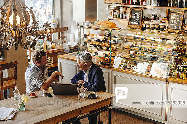 Two businessmen with laptop meeting in a cafe