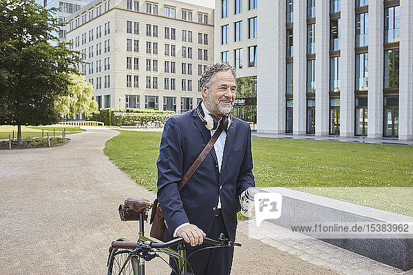 Älterer Geschäftsmann mit Fahrrad in der Stadt