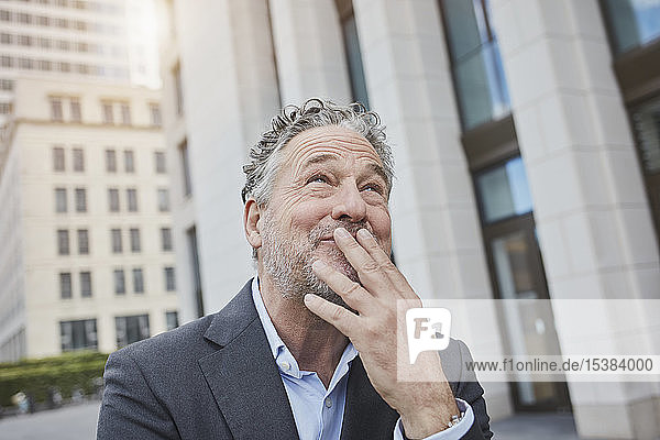 Porträt eines glücklichen Geschäftsmannes in der Stadt mit Blick nach oben